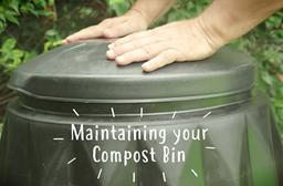 a hand placing a lid on top of a compost bin